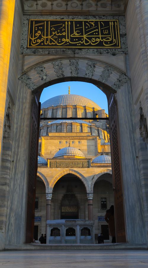 Free View of the Suleymaniye Mosque's dome in Istanbul, Turkey, captured through a grand arch at sunset. Stock Photo