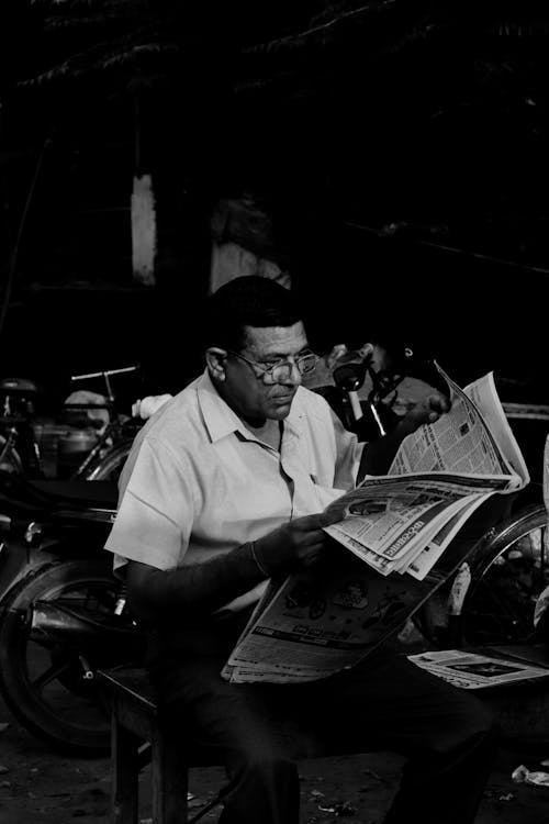Free Grayscale Photo of Man Reading Newspaper Stock Photo