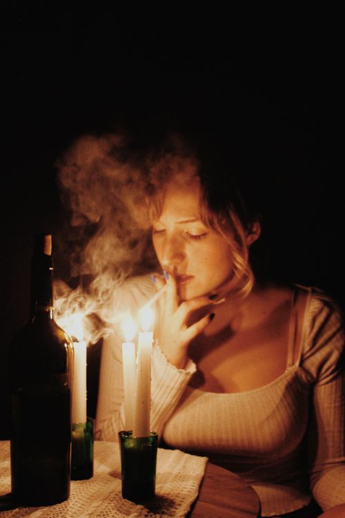 Free A woman illuminated by candlelight, surrounded by smoke in a dark, moody setting. Stock Photo