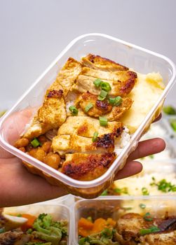 Appetizing grilled chicken with vegetables and rice in a plastic container.