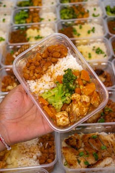 Colorful meal prep container with rice, beans, chicken, and vegetables for a balanced diet.