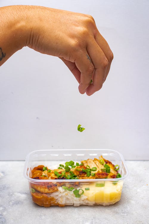 Hand Sprinkling Green Onions on Rice Dish · Free Stock Photo