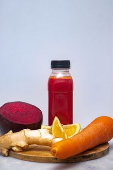Colorful still life image of fresh juice with beetroot, carrot, ginger, and orange.