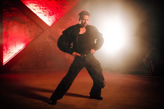 Man striking a powerful dance pose against a vibrant red backdrop with dramatic lighting.
