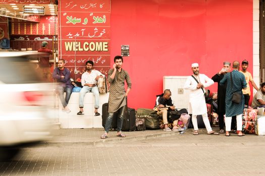 Busy street scene in Saudi Arabia with people and luggage near a storefront.