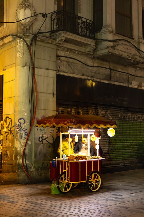 Free Street food vendor in a lively urban area at night with warm lights and graffiti. Stock Photo