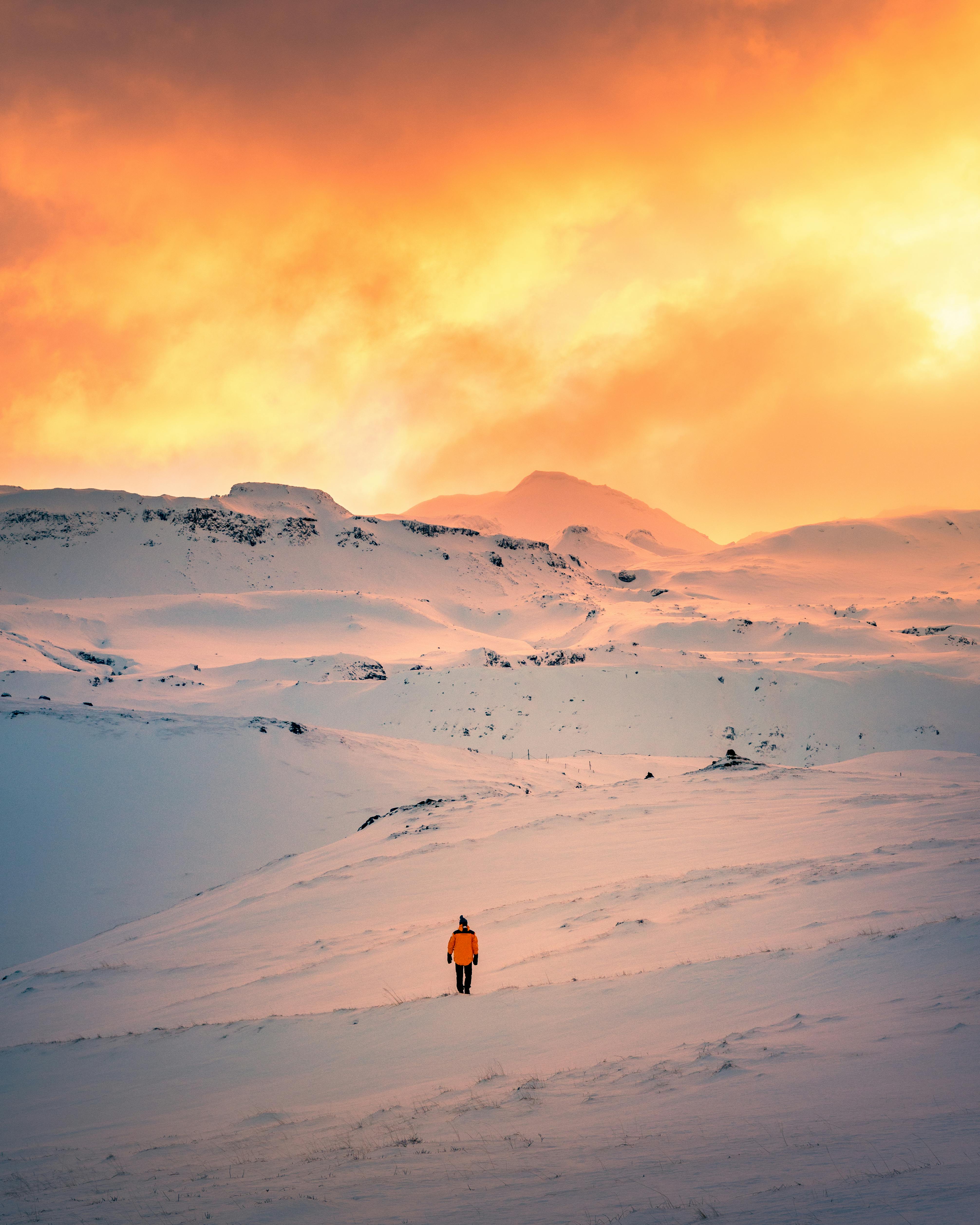 Stunning sunset over snowy landscape in Grundarfjörður, Iceland with a lone hiker.