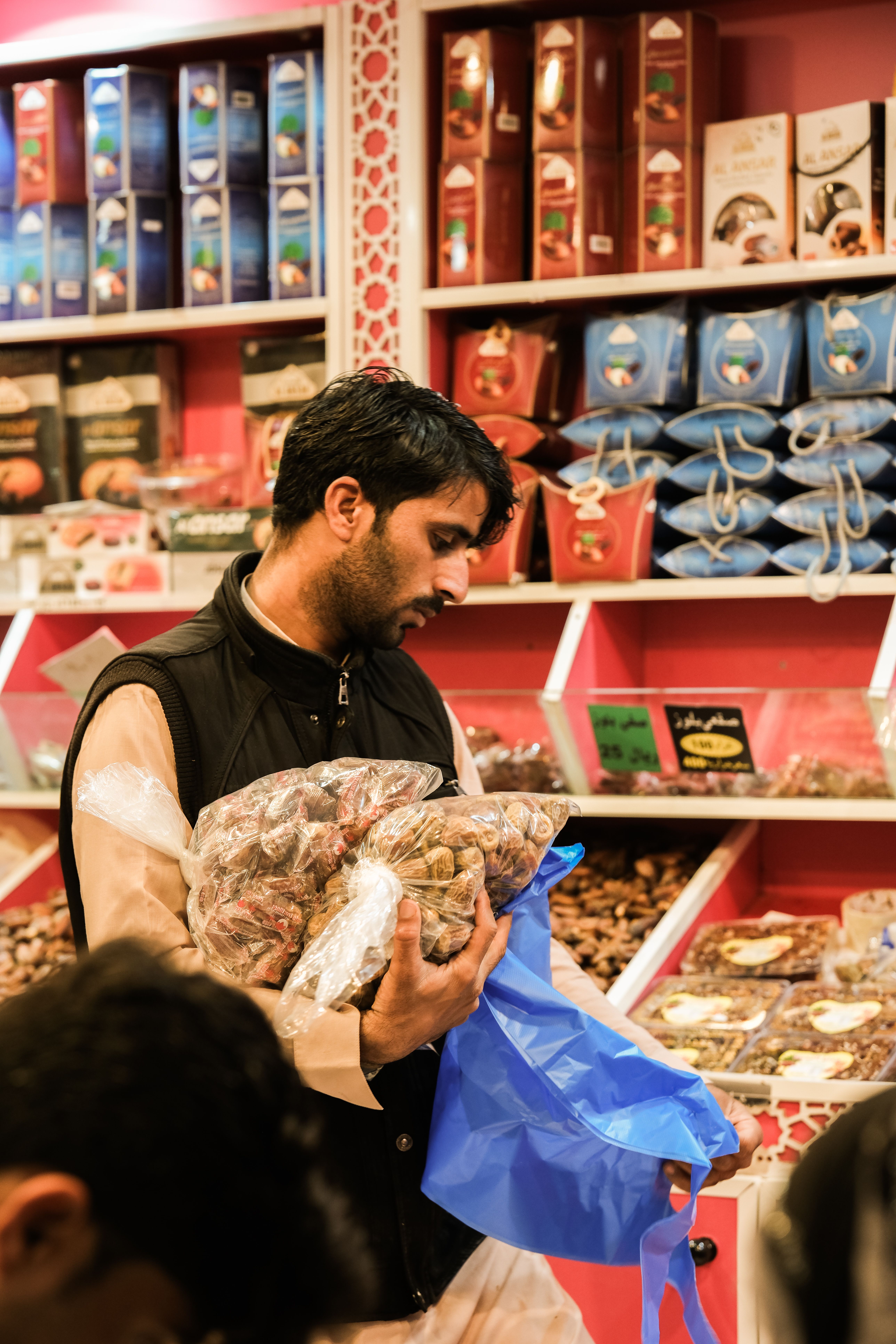 Man shopping for nuts and dried fruits in a bustling Saudi Arabian market. - How to Tell if Dry Fruits Have Gone Bad