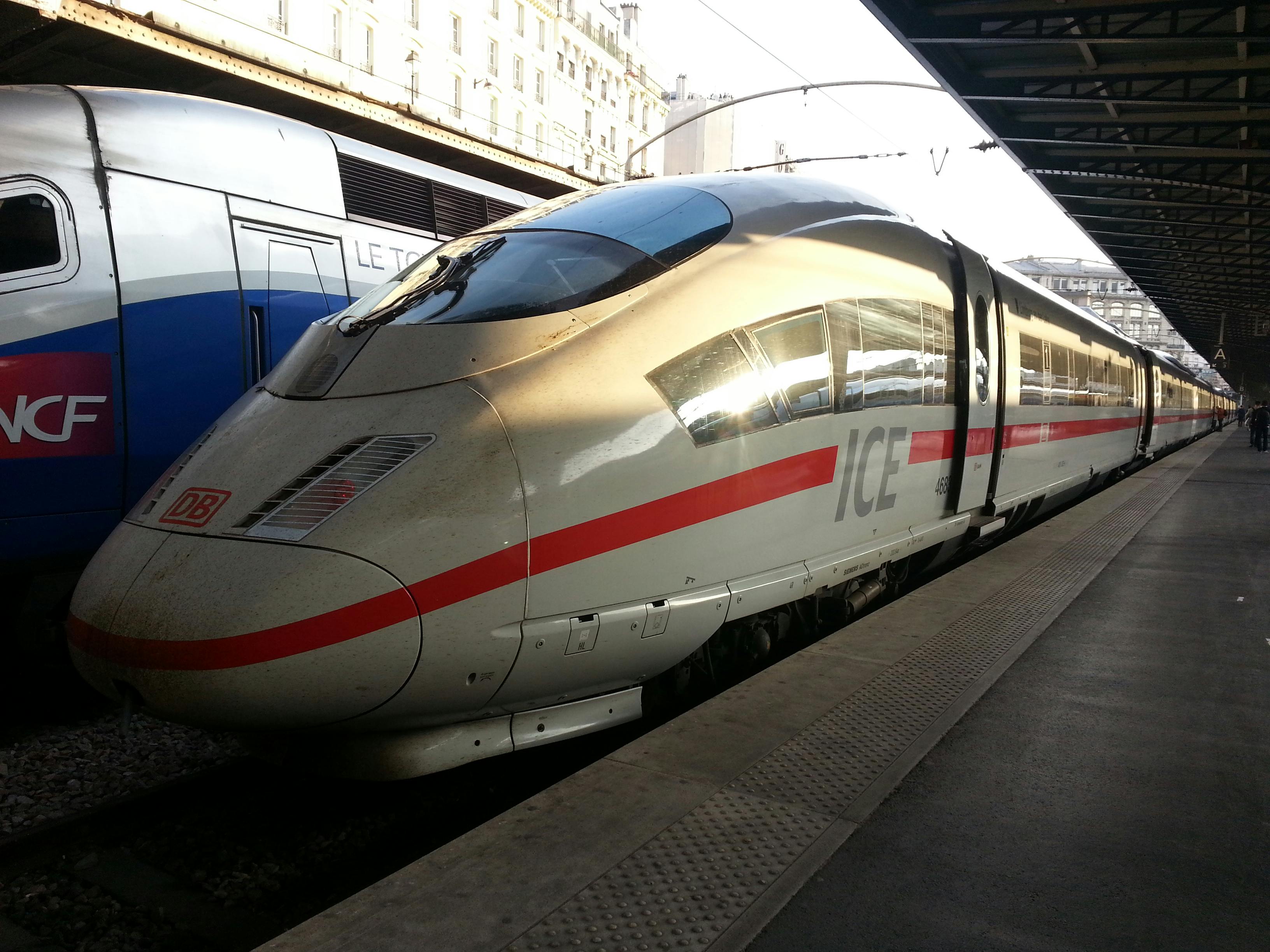 Elegant ICE high-speed train at a station platform under sunlight, ready for departure.