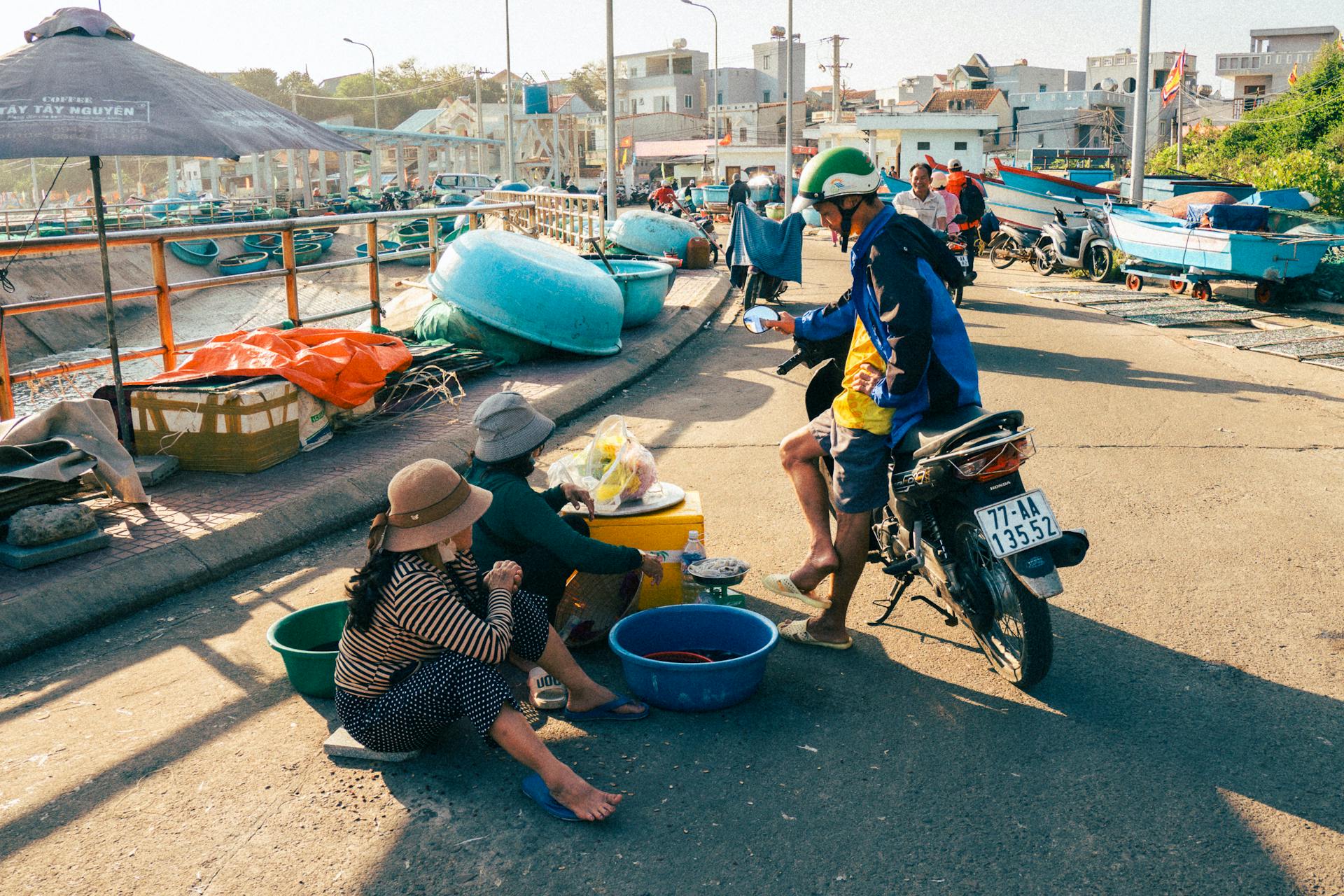 Vibrant outdoor market on a sunny day in Quy Nhơn, Vietnam, showcasing colorful boats and local life.