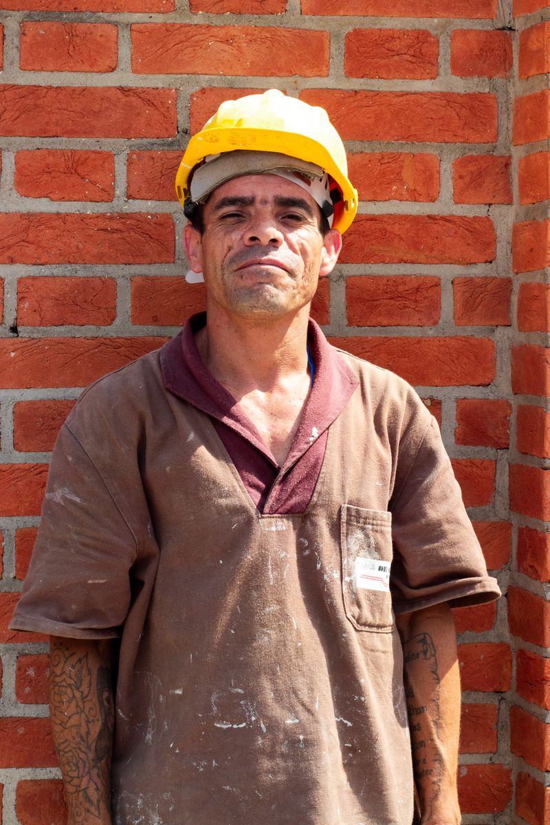 Profissional da construção civil em frente a parede de tijolos