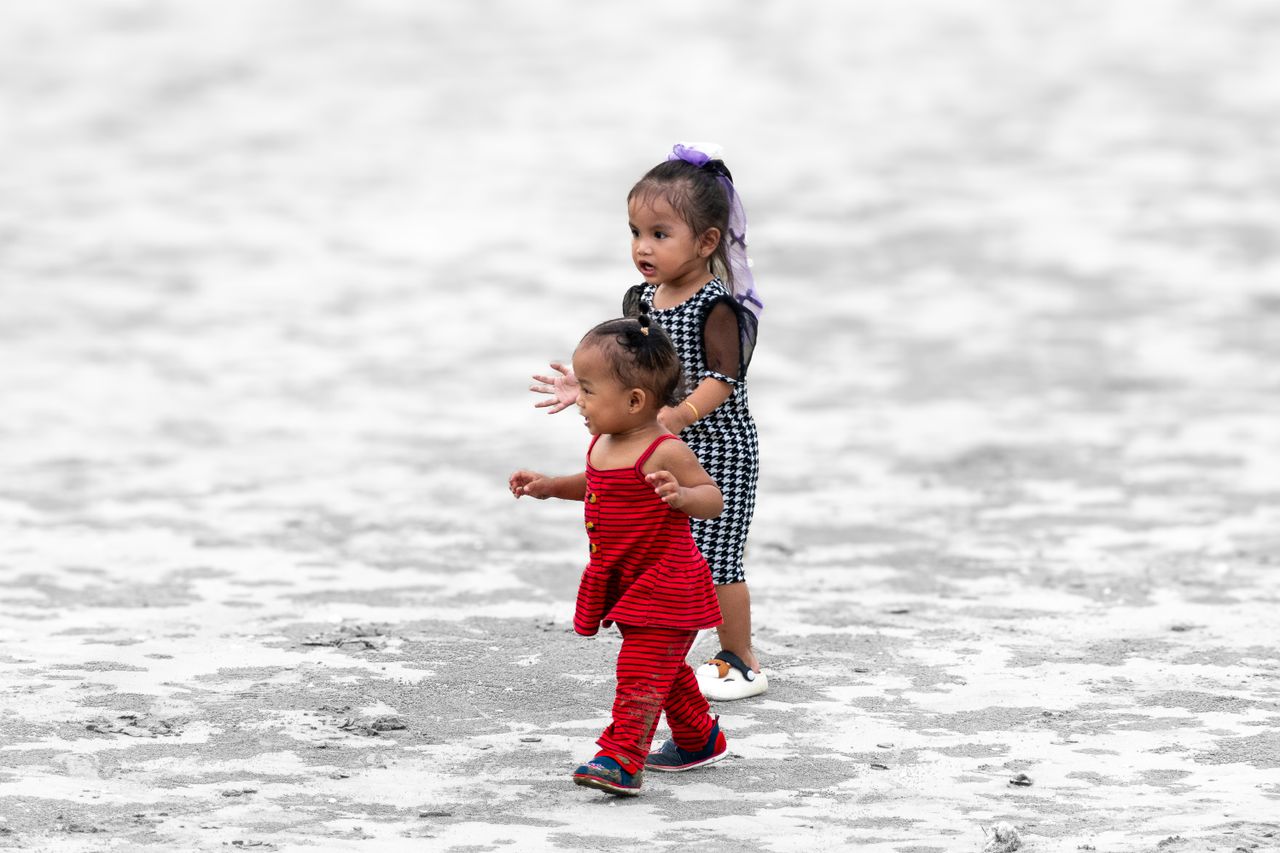 two young children walking on sandy ground dressed in stylish clothing