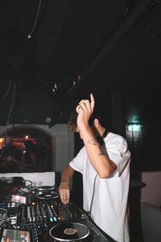 Energetic DJ spinning tracks in a lively club with flashing lights and a vibrant crowd.