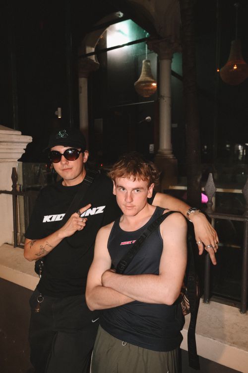 Free Two friends pose together outside a nightclub at night, showcasing modern fashion. Stock Photo
