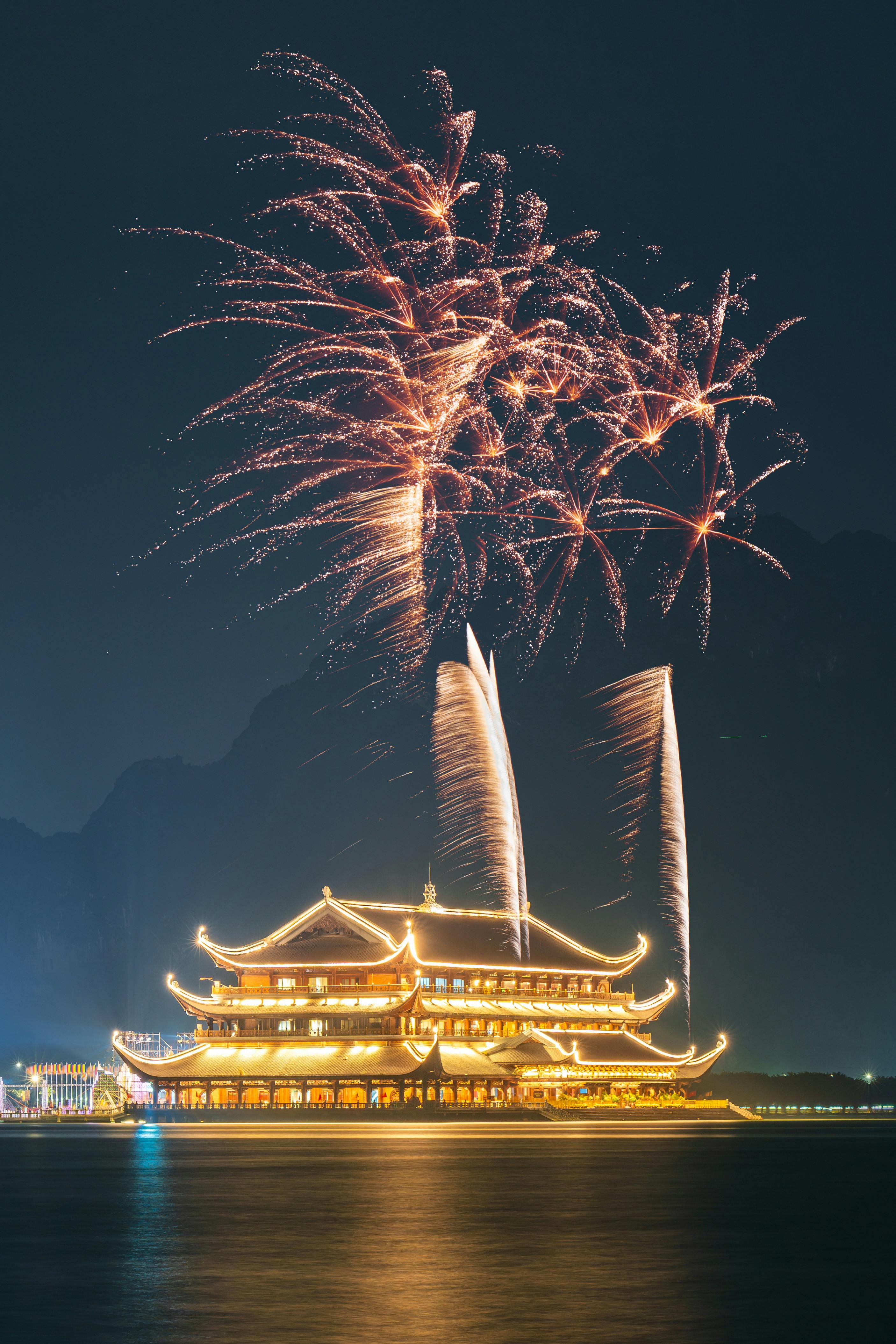 Vibrant fireworks display above the illuminated pagoda at Tam Chúc in Hà Nam, Vietnam, showcasing cultural splendor.