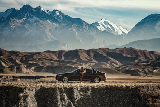 一名女子站在汽车旁，背景是令人惊叹的山脉，体现了探索和旅行精神