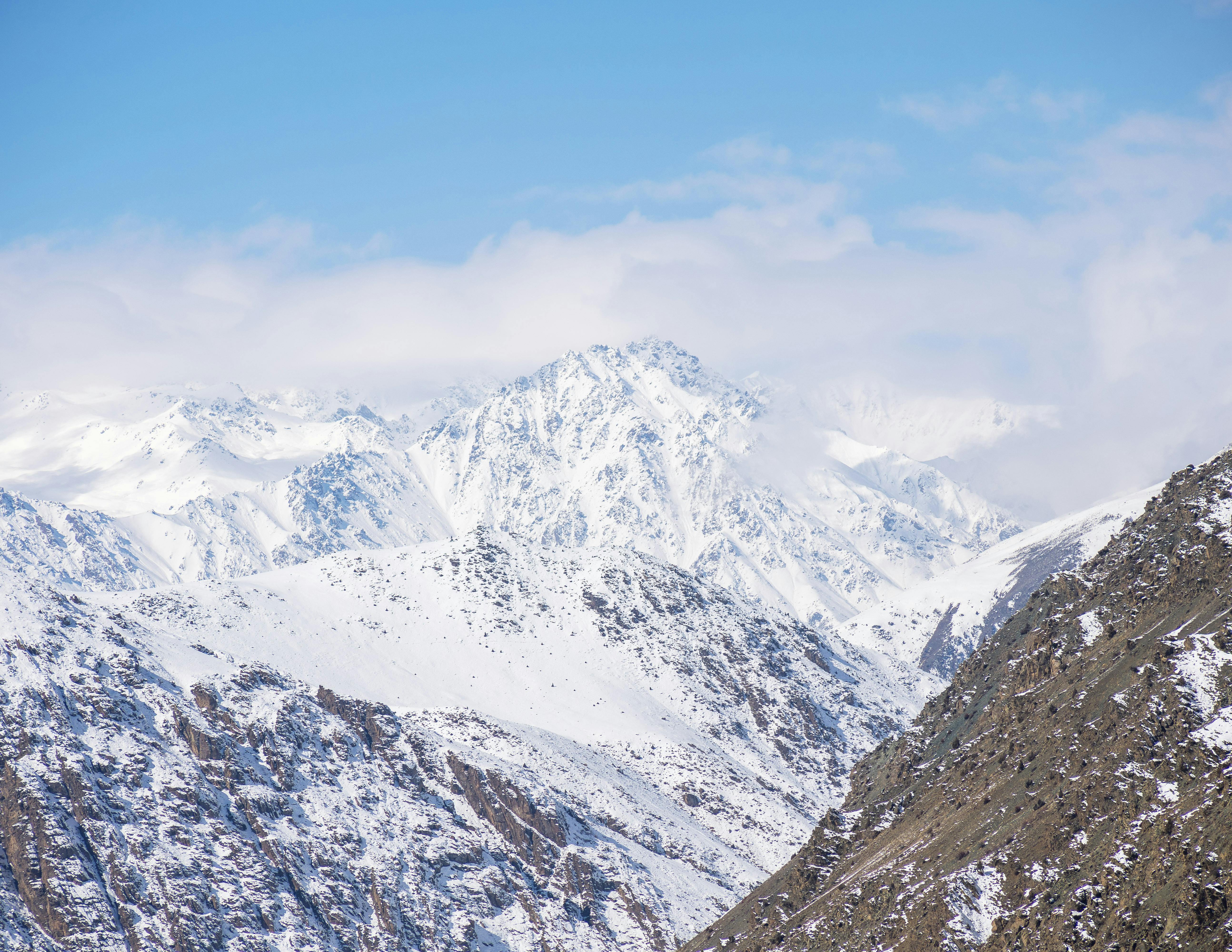 A serene view of snow-covered mountain peaks under a clear blue sky.