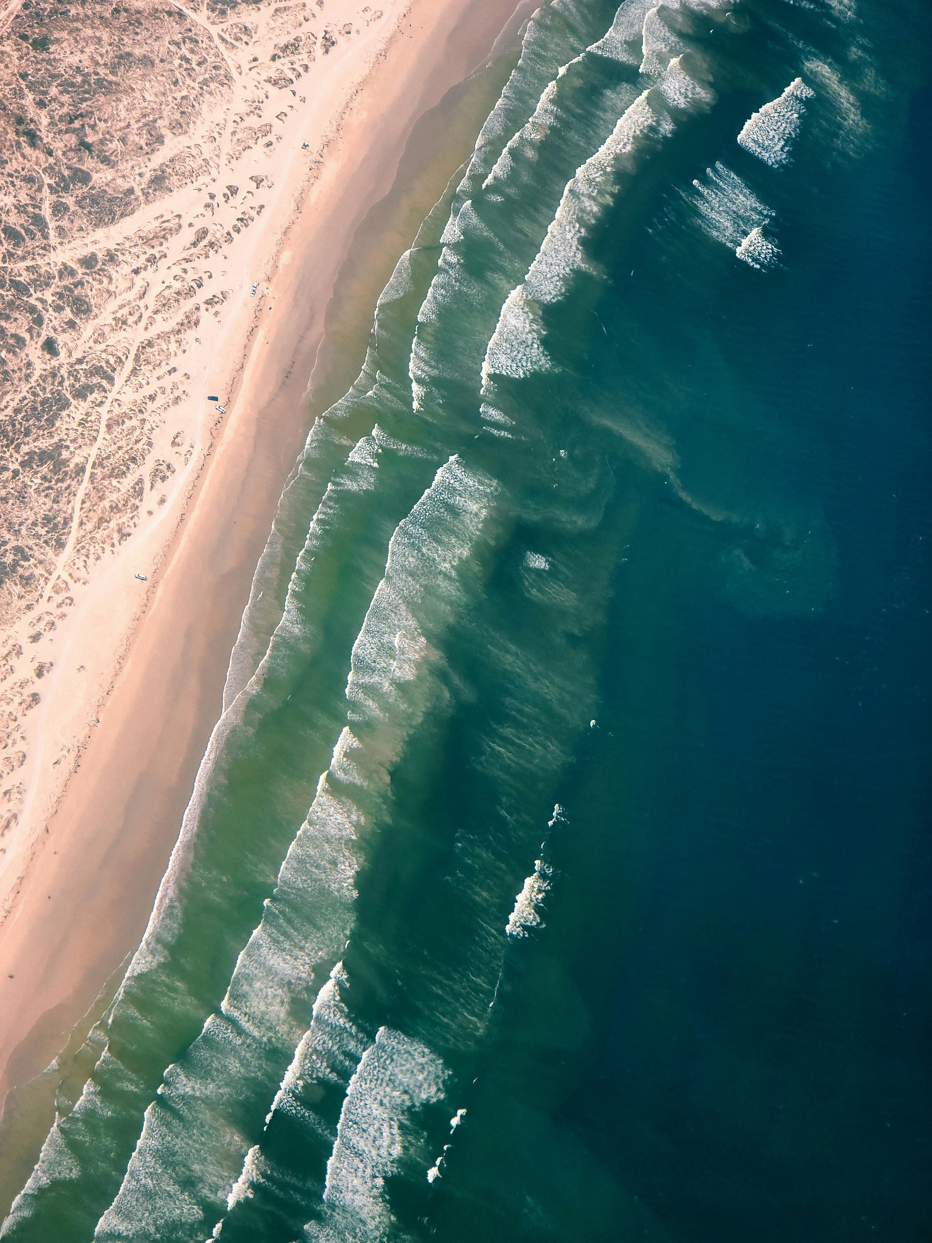 Aerial shot capturing the dynamic waves and sandy coast of Cape Town's beach.