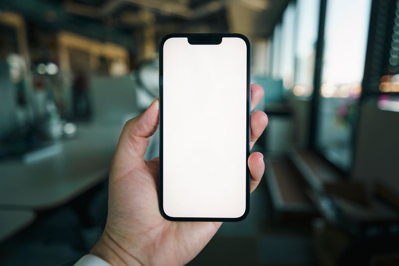 Hand holding a smartphone in a modern office