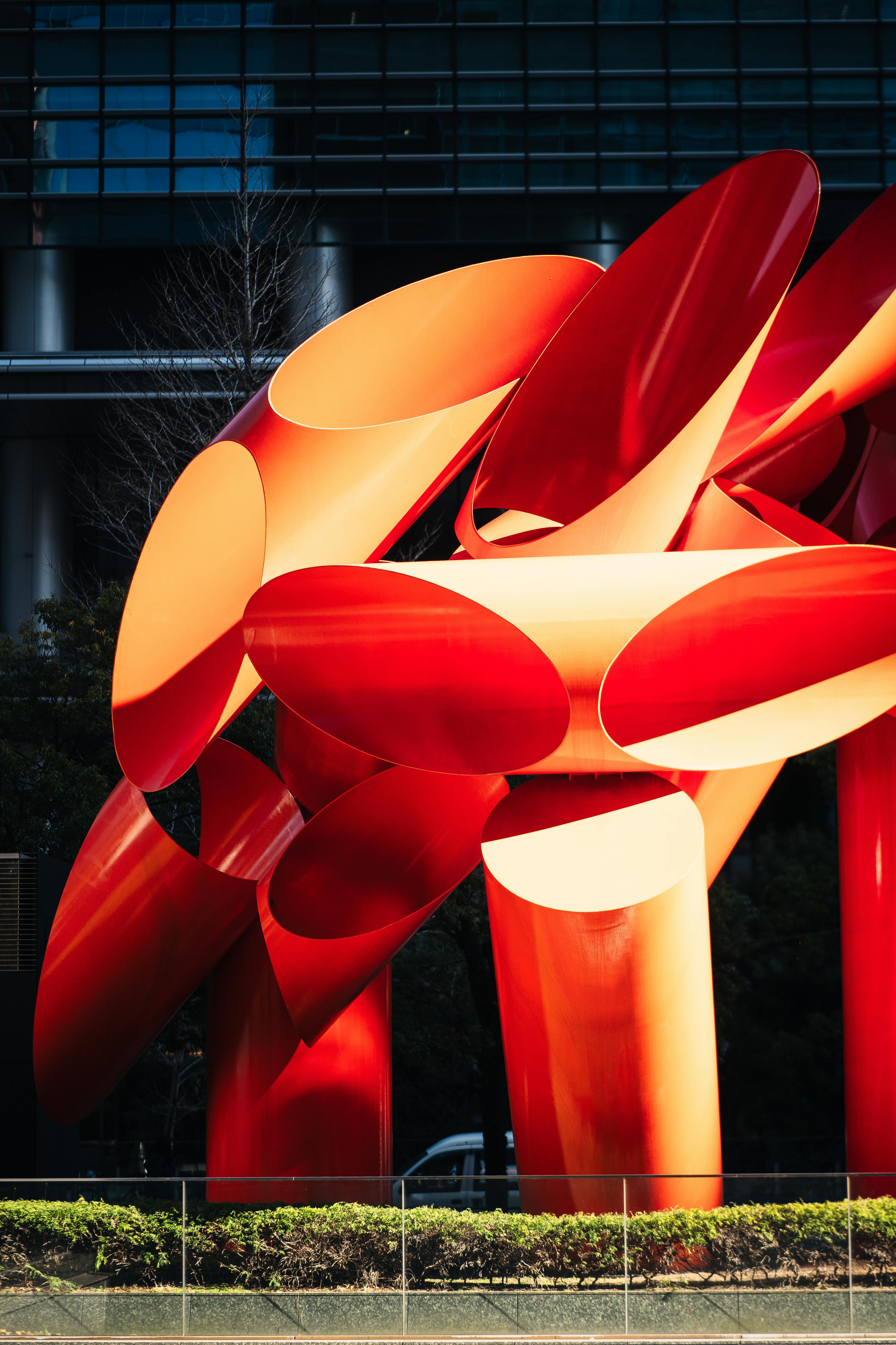 Vibrant red abstract sculpture in Tokyo's urban setting, exemplifying modern art design.