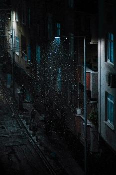 Rain falling under a streetlight in a dark urban alley, creating a mysterious ambiance.