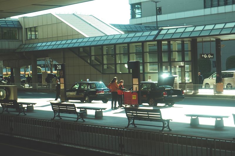 Cars waiting at a terminal kerbside at dusk while passengers load bags, photo by John One on Pexels