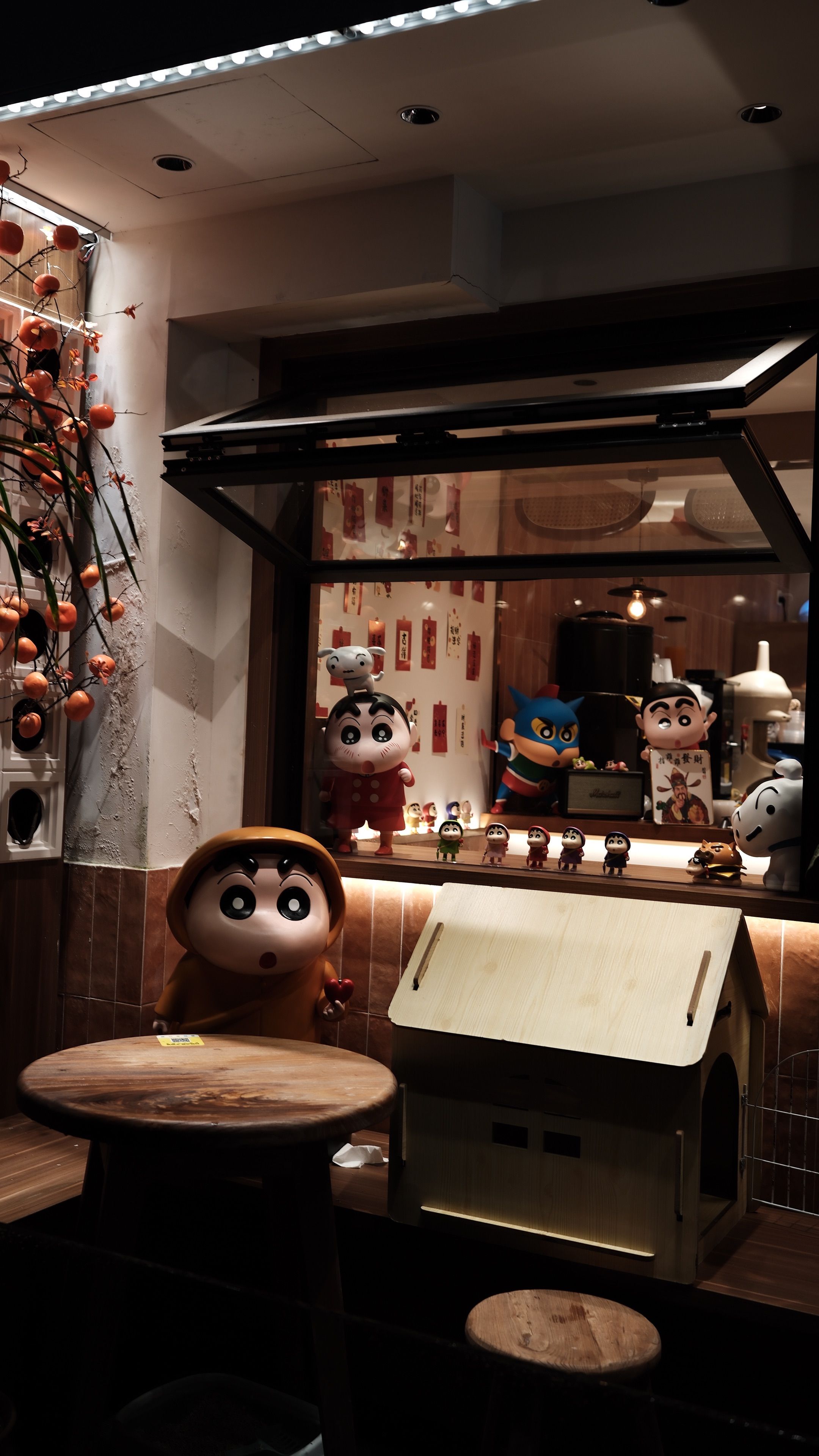 Cozy cafe window display with anime figures at night, exuding a warm, inviting ambiance.