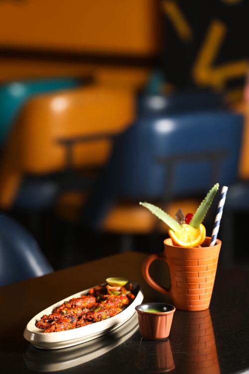 Free Sizzling chicken wings with a fresh citrus drink on a restaurant table. Stock Photo