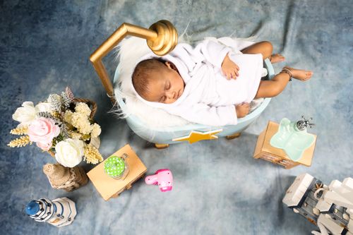 Free Cute baby sleeping peacefully in a cozy bath-themed setting with toys and floral decor. Stock Photo