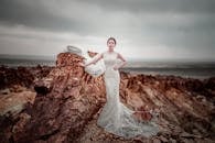 一名女子身穿优雅的白色连衣裙，与一只狗在引人注目的岩石景观前合影