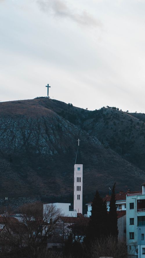 Free Church tower with a cross on a mountain in the background, scenic religious view. Stock Photo