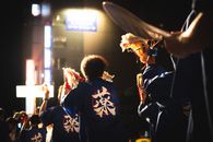 A vibrant night festival with traditional dancers in Japan under city lights.