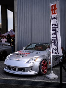 Modified silver sports car at a Japanese car show with custom features and decals.
