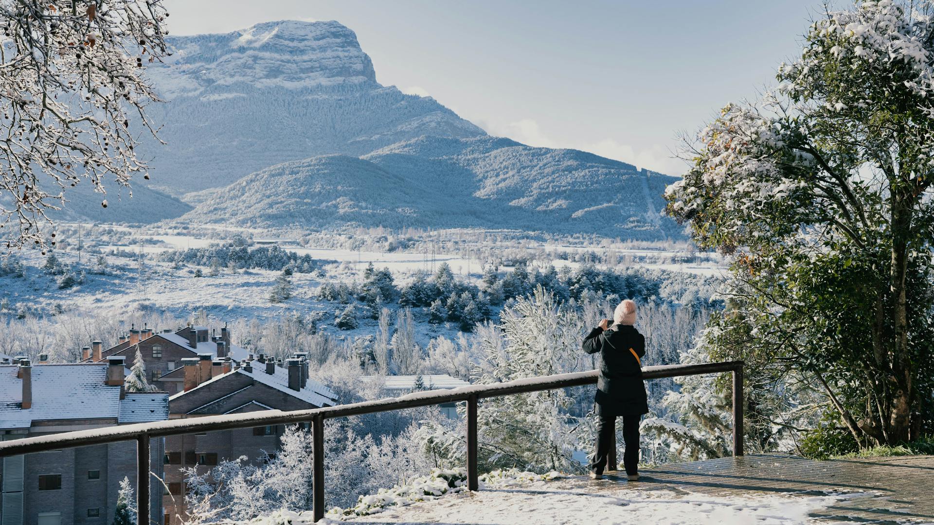 A person photographing a snowy mountainous landscape in Jaca, Aragón.