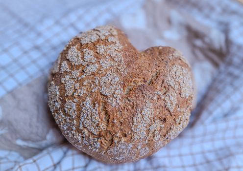 Close-up of a crusty artisan loaf with a rustic texture placed on a checkered cloth.