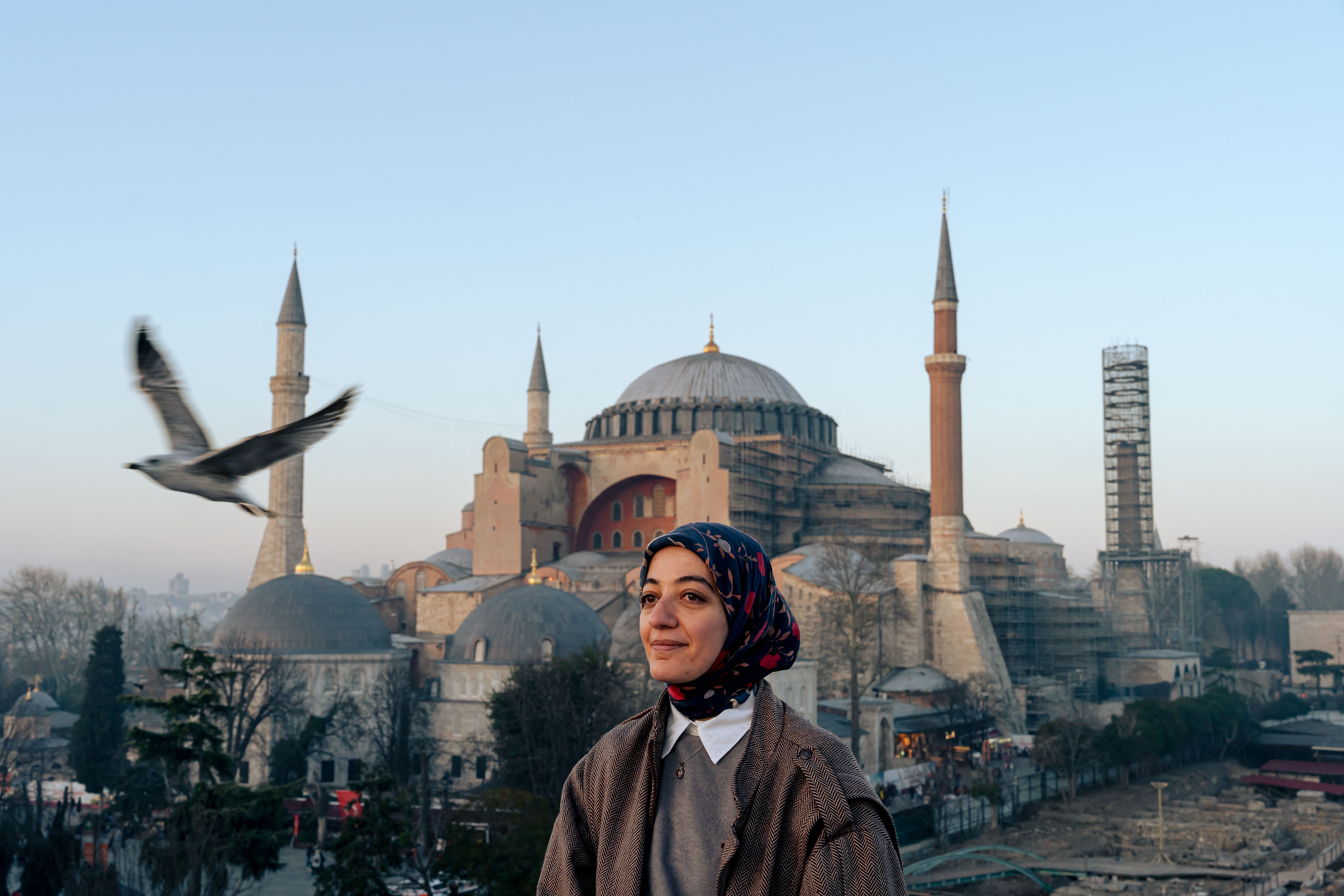 A woman smiles near the majestic Hagia Sophia at sunrise in Istanbul, Turkey.