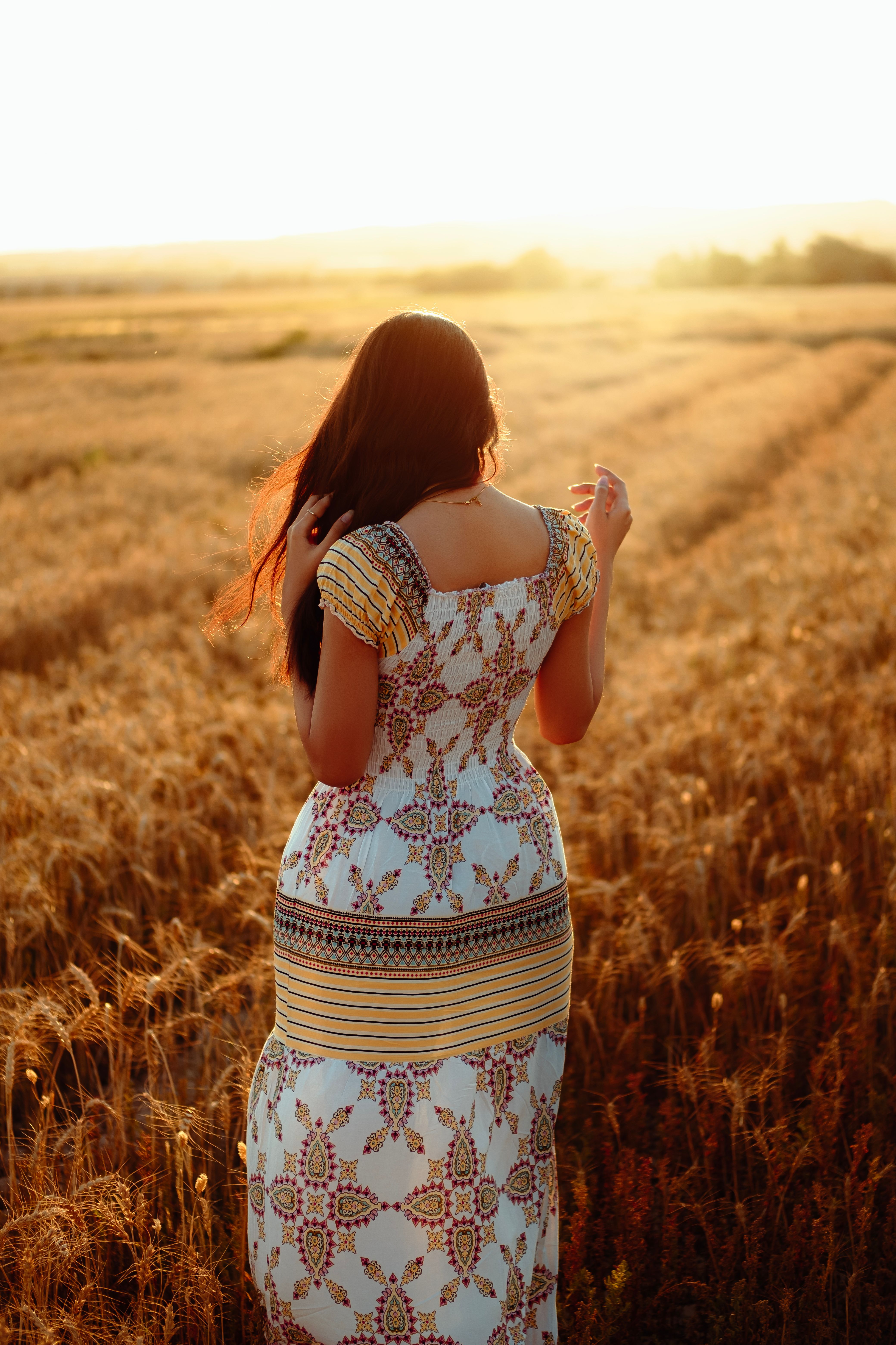 Woman Strolling Through Golden Wheat Field at Sunset · Free Stock Photo