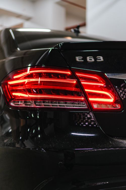 Free Detailed shot of a car tail light and E63 badge in an indoor parking area. Stock Photo