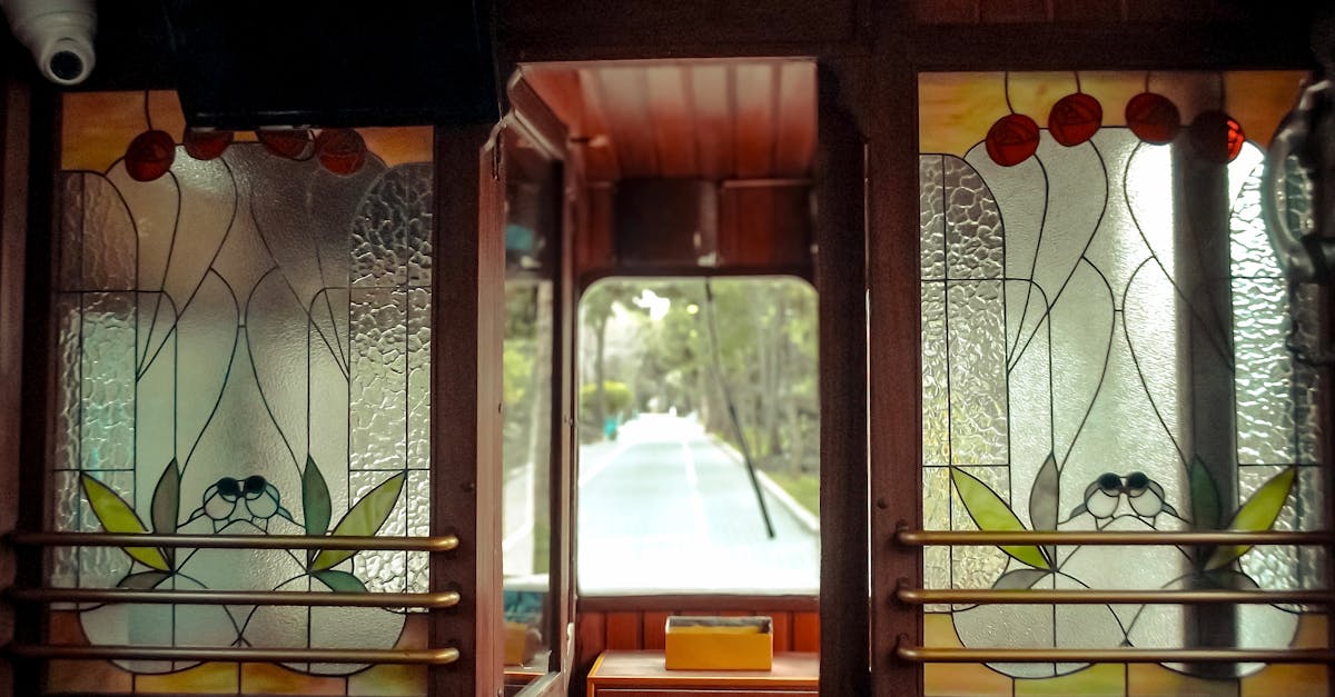 Interior view of a vintage train with colorful stained glass windows and a scenic outdoor view.