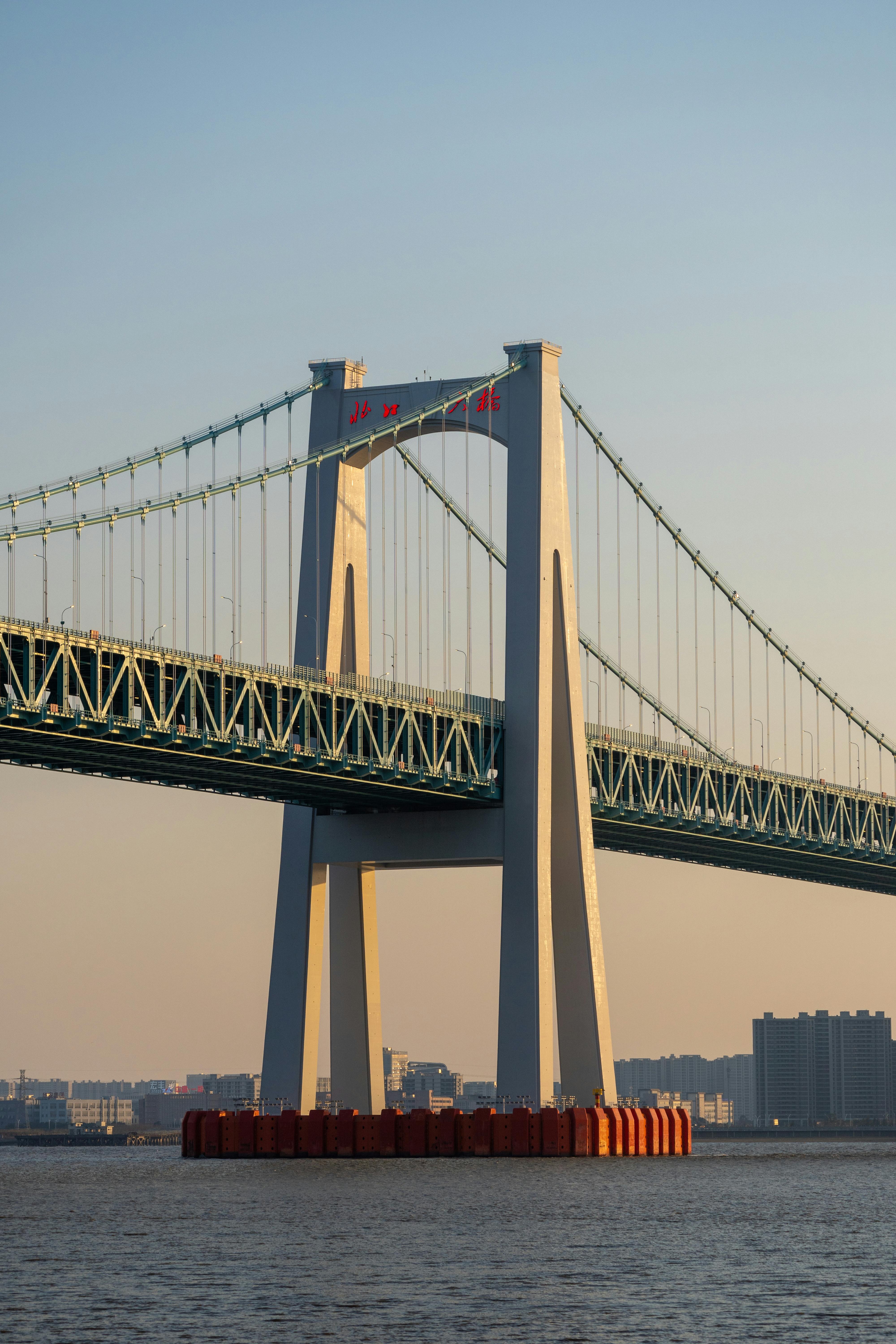 suspension bridge over urban river at sunset