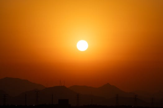 Captivating sunset over silhouetted mountains with power lines.