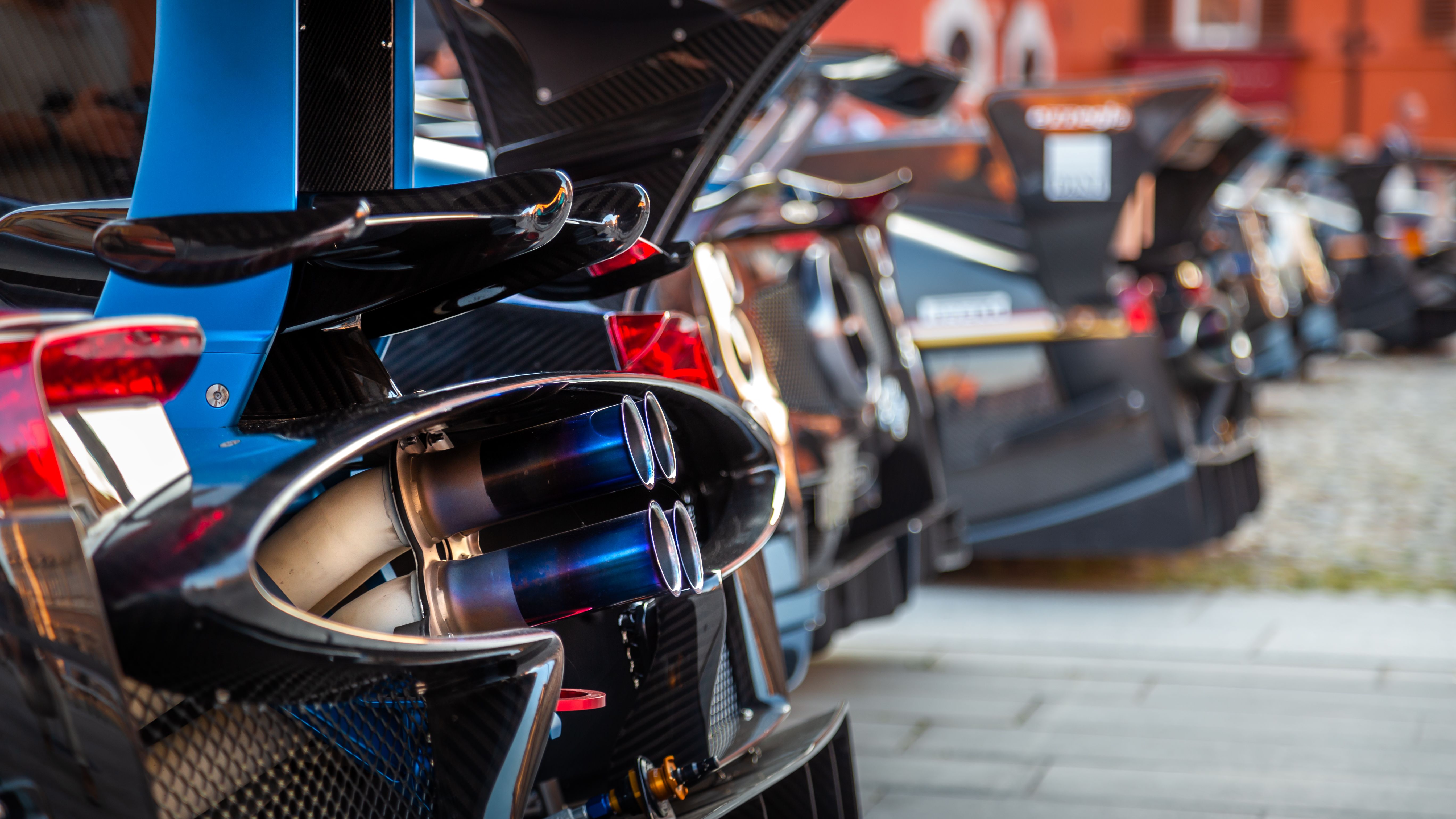 Detailed view of a supercar exhaust at an outdoor automobile exhibition.