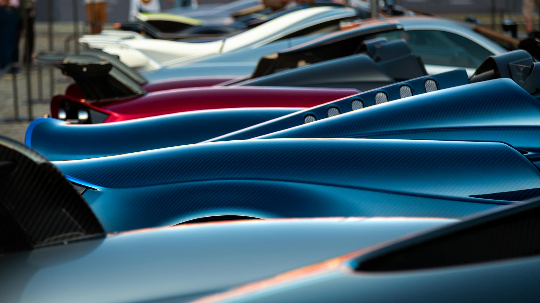 A stunning display of sleek hypercars showcasing premium designs and vibrant colors at an exhibition.