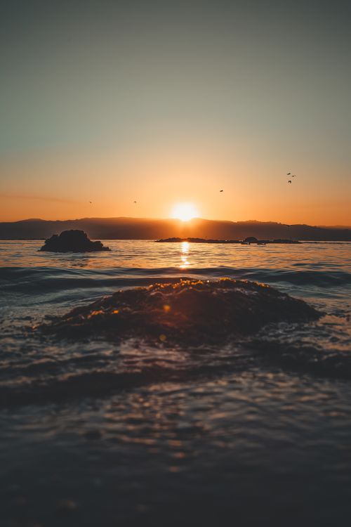 Free Captivating sunrise over the ocean with gentle waves and a peaceful atmosphere. Stock Photo