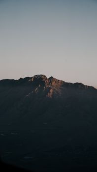 A mountain range bathed in soft dusk light, captured in a serene landscape setting.