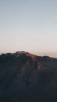 A serene view of a sunlit mountain range under a clear sky during golden hour.