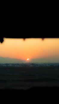 Dramatic orange sunset over a distant cityscape creates a serene silhouette.