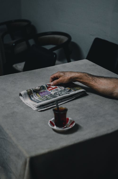 Free Person Holding Newspaper on Table Stock Photo