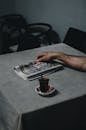 Person Holding Newspaper on Table