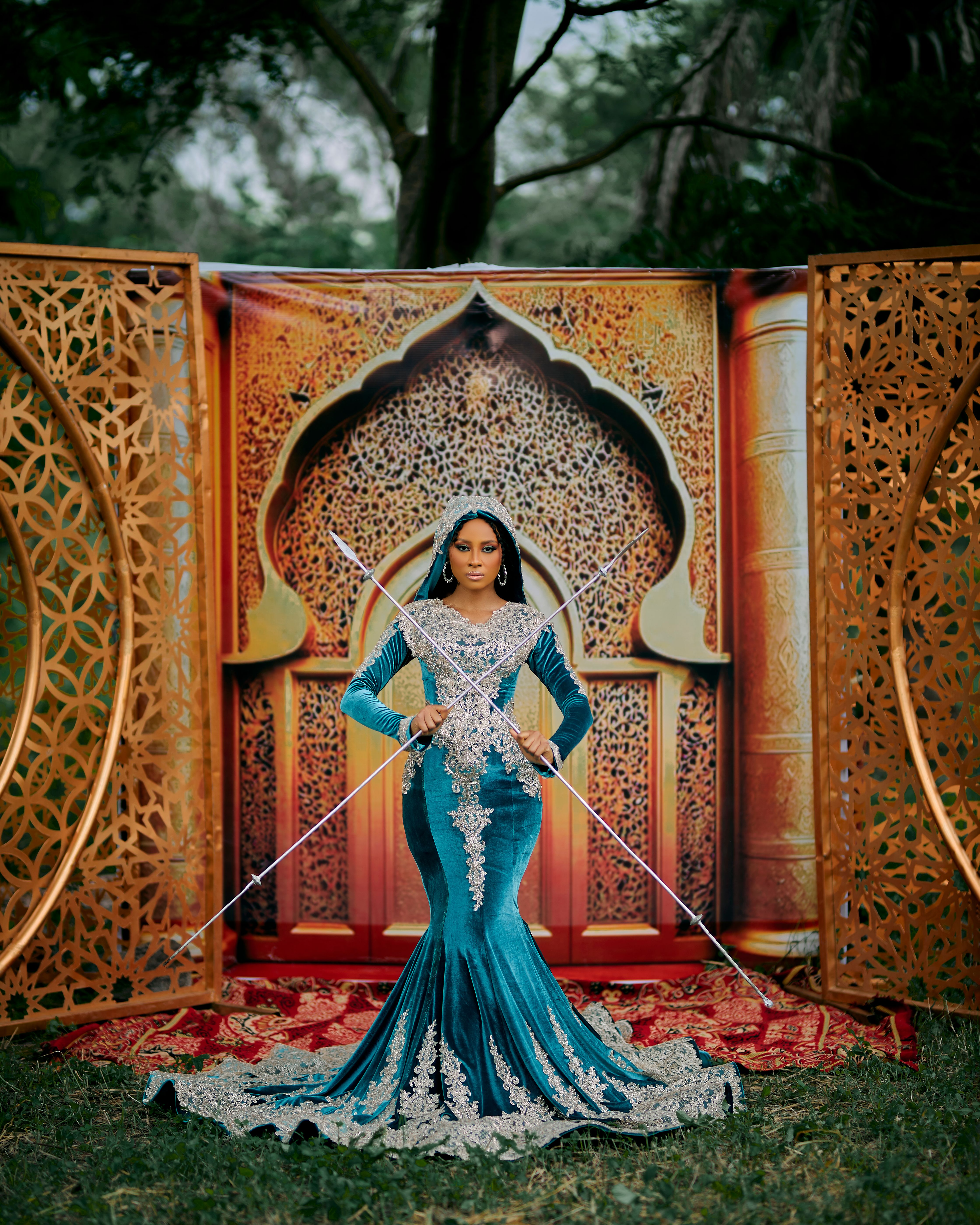 A woman in a stunning dress poses in front of intricate golden archways, blending elegance and tradition.